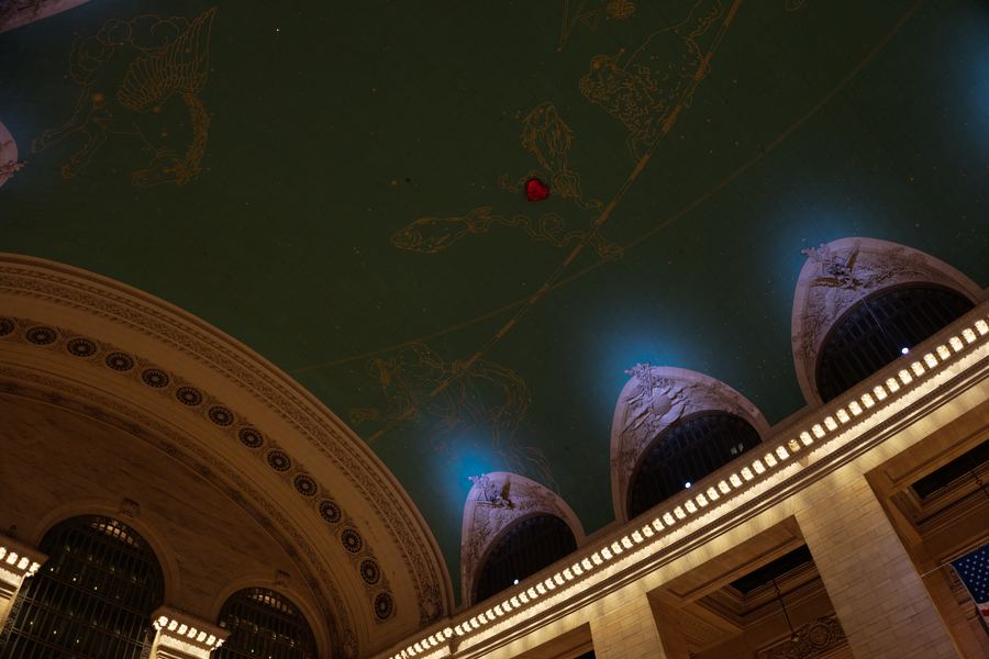 The green and gold constellation ceiling of Grand Central above lit arches.