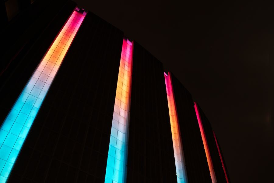 Bands of cyan and orange light running up a dark curved wall.