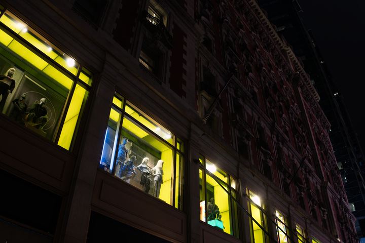 Acid yellow shop windows raking up a dark stone facade.